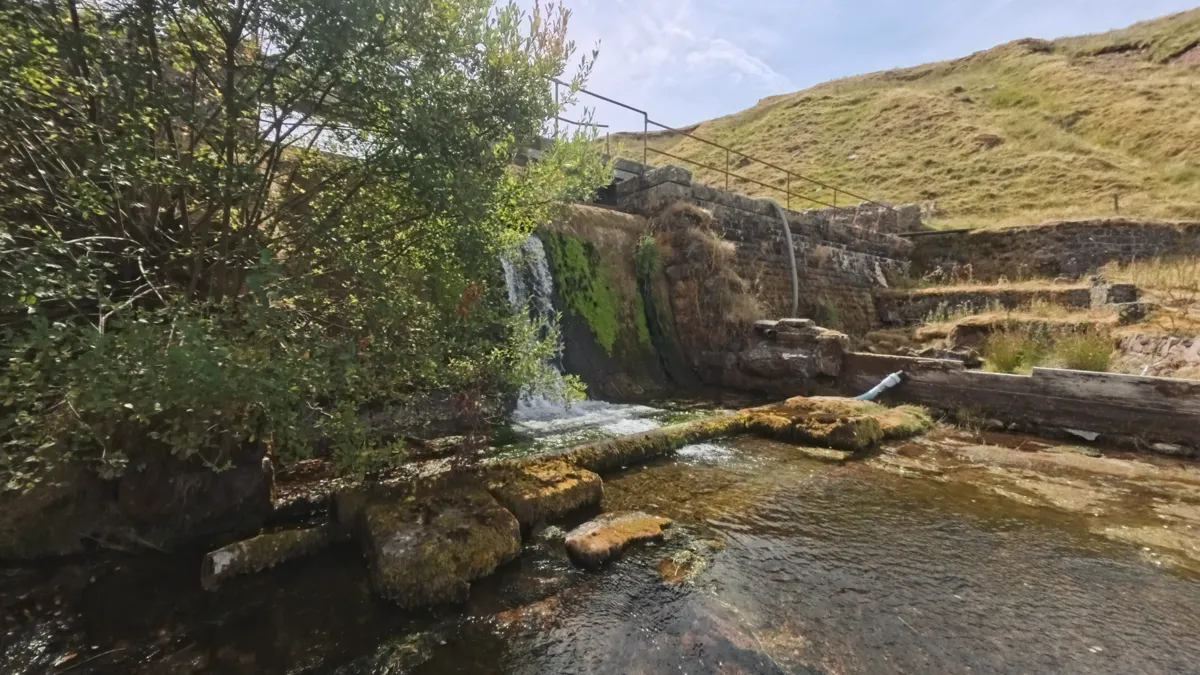 Water spilling over a mossy stone weir at the old waterworks beside the walk-in track