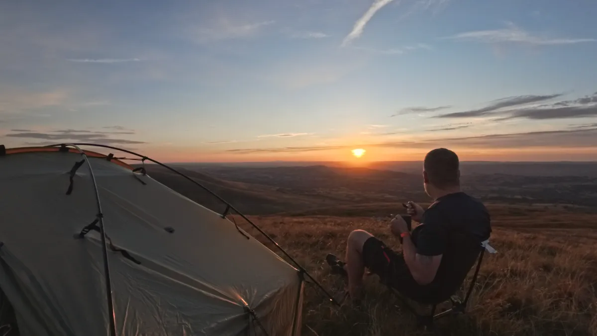Sitting outside the tent at dusk watching the sun set over the lowlands far below