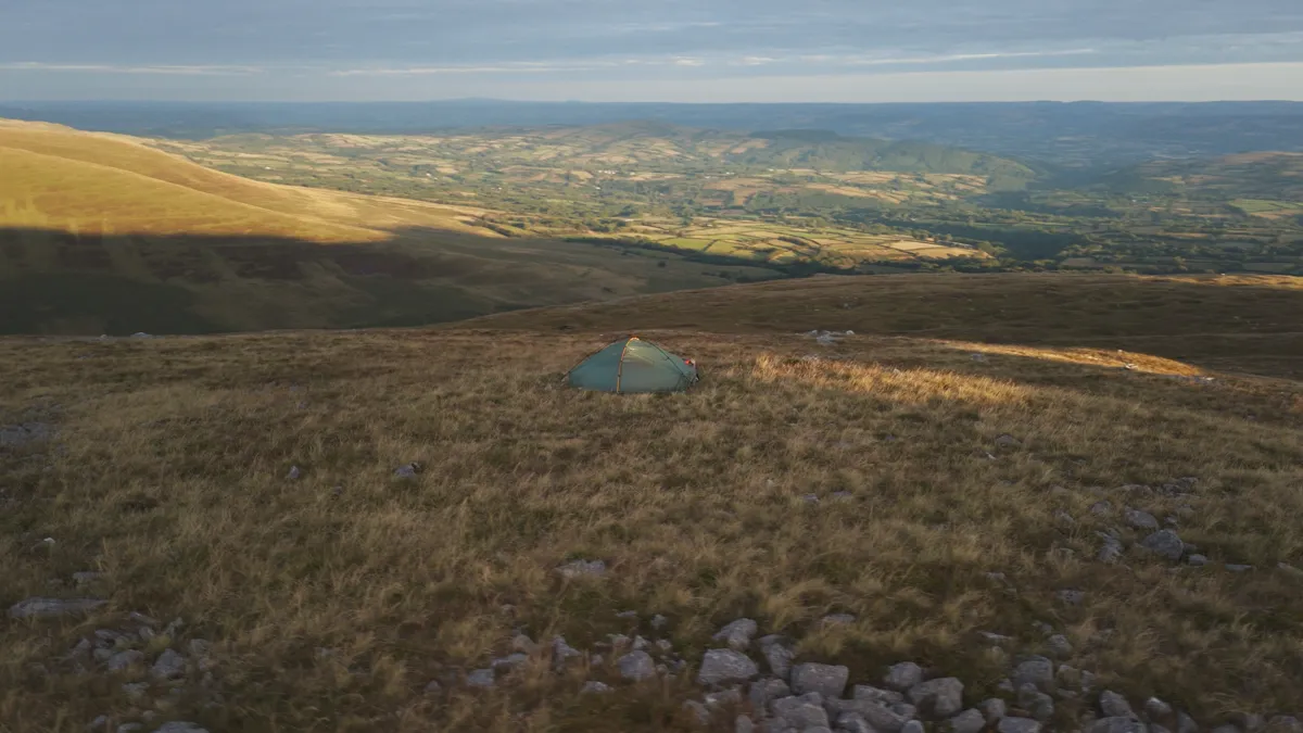 A small tent alone on a vast empty hillside with nobody else in sight